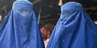 An Afghan vendor displays a burqa at his shop