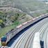 A passenger train travels along the standard gauge railway line at Miritini Station.