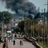 People cross a bridge over the Oskil River as smoke rises in city of Kupiansk